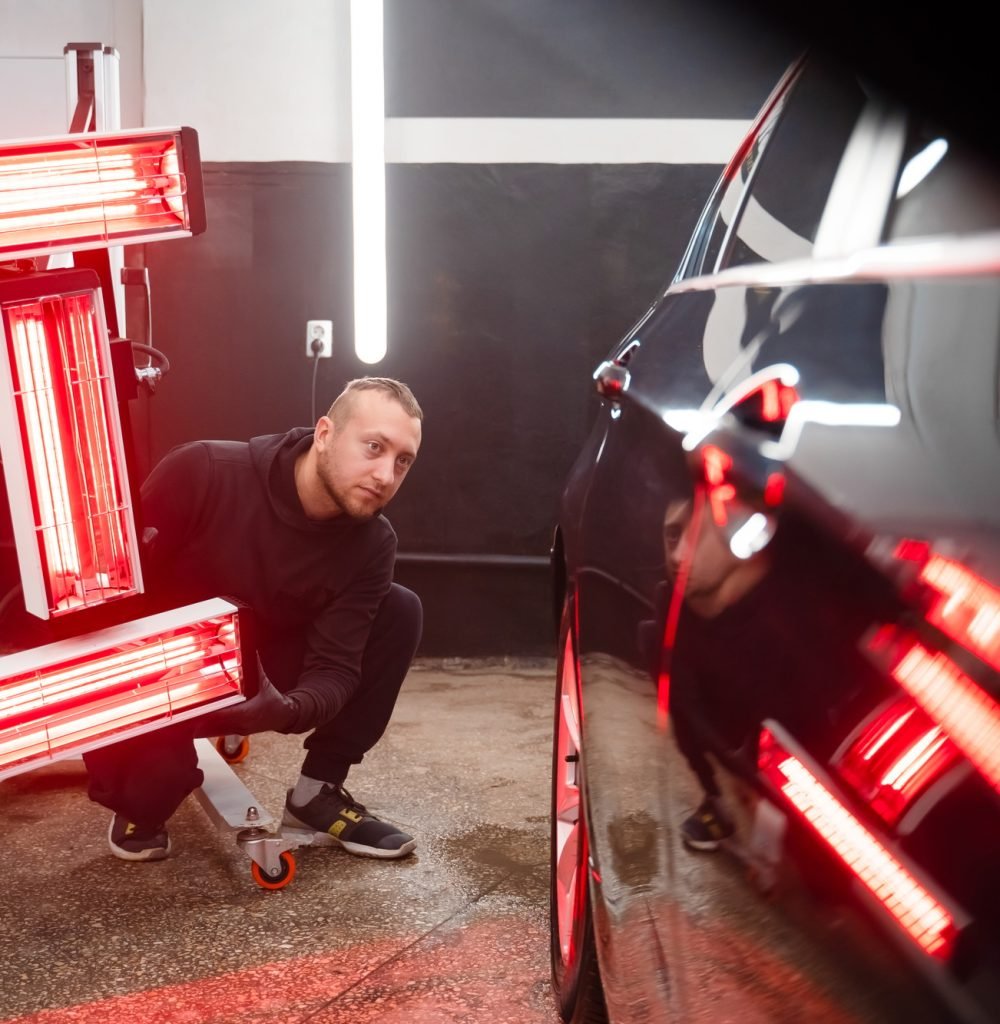 Detailing worker with infrared lamps near the car. Car detailing concept